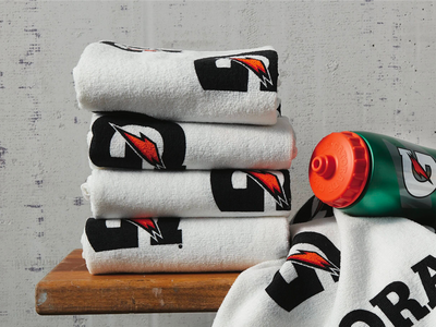 Stack of white Gatorade premium sideline towels beside a Gatorade bottle